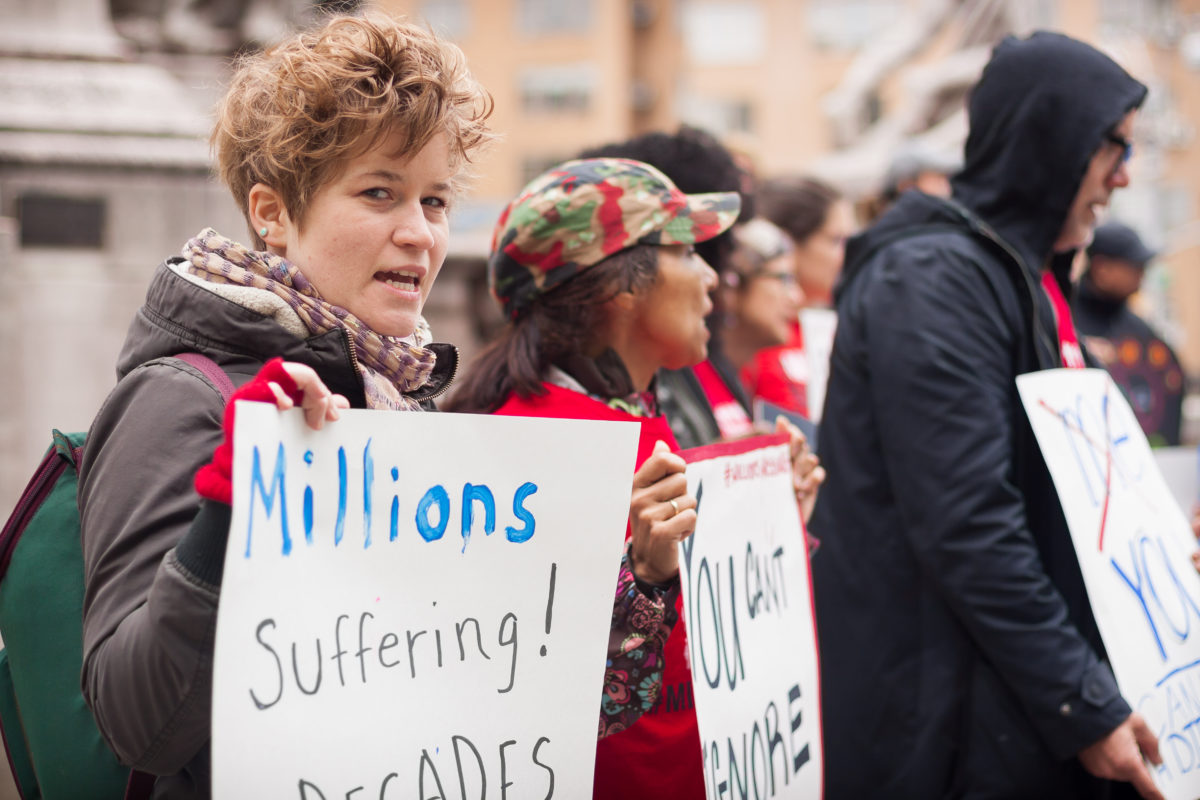woman in line of protestors holds sign,